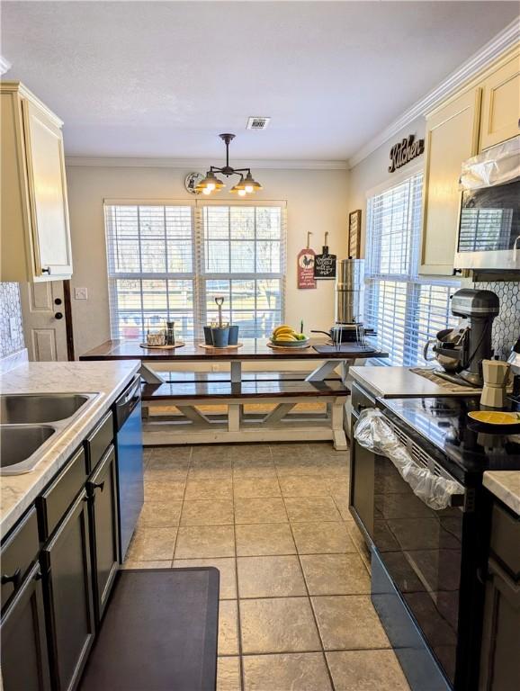 kitchen featuring cream cabinetry, light tile patterned flooring, ornamental molding, and stainless steel appliances