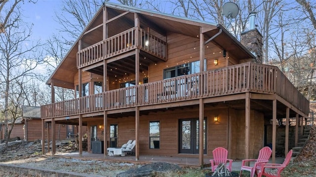 rear view of house featuring a deck, a patio, a chimney, and cooling unit