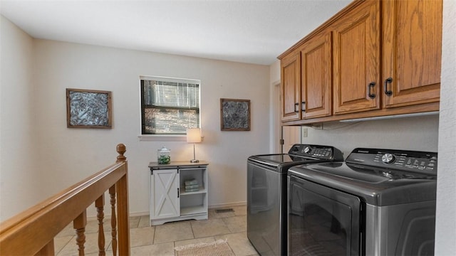 laundry room featuring cabinet space, visible vents, baseboards, washing machine and clothes dryer, and light tile patterned flooring