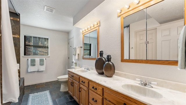 bathroom with a textured ceiling, toilet, stone tile floors, a sink, and visible vents