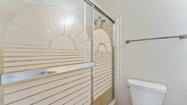 full bath featuring a textured wall, an enclosed shower, and toilet