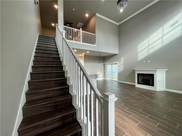 staircase with an inviting chandelier, a high ceiling, and ornamental molding