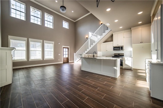 kitchen with a healthy amount of sunlight, white cabinetry, stainless steel appliances, and an island with sink