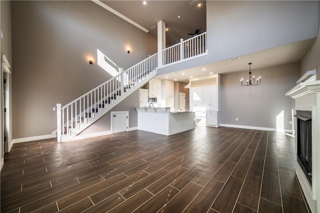 unfurnished living room featuring ceiling fan with notable chandelier and a high ceiling