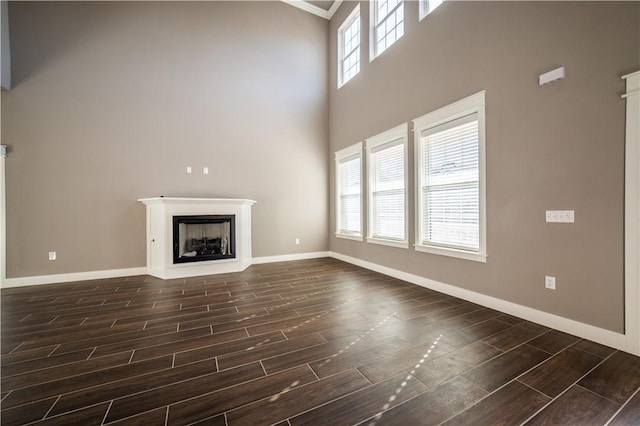 unfurnished living room with plenty of natural light, ornamental molding, and a high ceiling