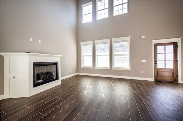 unfurnished living room with a towering ceiling and dark hardwood / wood-style floors