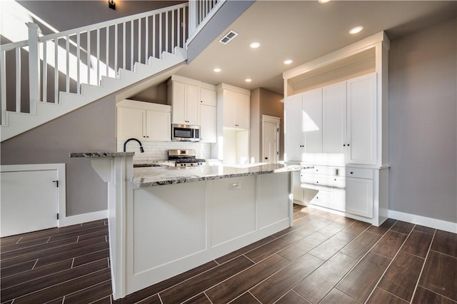 kitchen with white cabinets, light stone countertops, sink, and appliances with stainless steel finishes