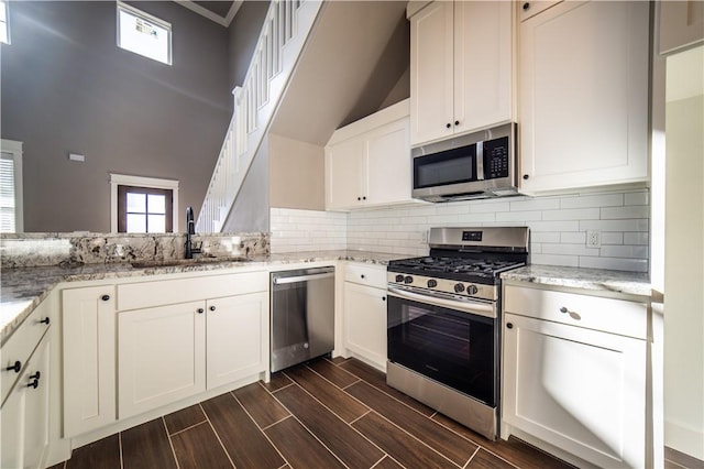 kitchen with decorative backsplash, light stone counters, sink, and appliances with stainless steel finishes