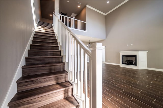 staircase featuring a chandelier, a towering ceiling, and ornamental molding