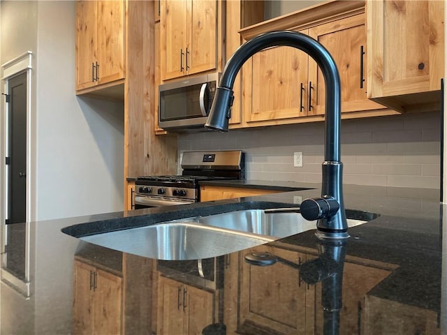 kitchen with backsplash, appliances with stainless steel finishes, and dark stone counters