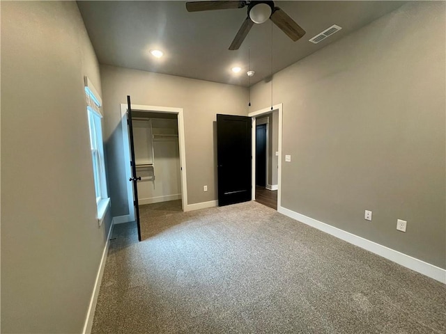 unfurnished bedroom with ceiling fan, multiple windows, carpet floors, a walk in closet, and a closet