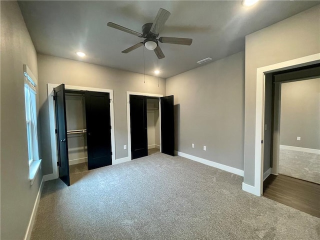 unfurnished bedroom with carpet flooring, ceiling fan, and multiple closets