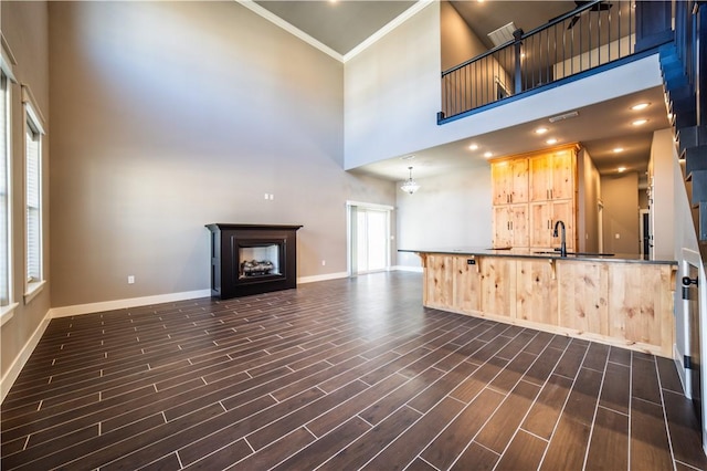 kitchen with crown molding, sink, light brown cabinets, an inviting chandelier, and a high ceiling