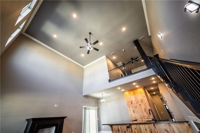 stairway featuring hardwood / wood-style floors, ceiling fan with notable chandelier, a towering ceiling, and ornamental molding