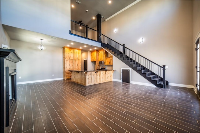 unfurnished living room with crown molding, a high ceiling, and a chandelier