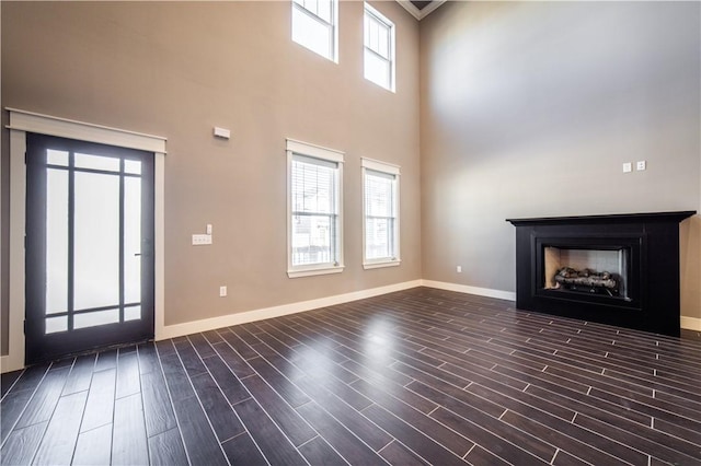 unfurnished living room with a towering ceiling and ornamental molding