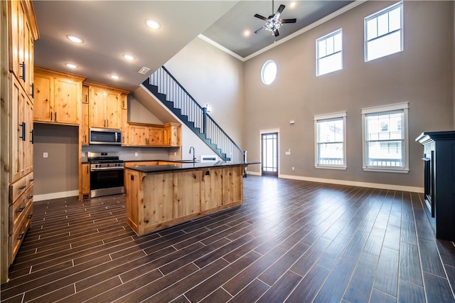 kitchen with sink, stainless steel appliances, a kitchen island with sink, a breakfast bar, and ornamental molding