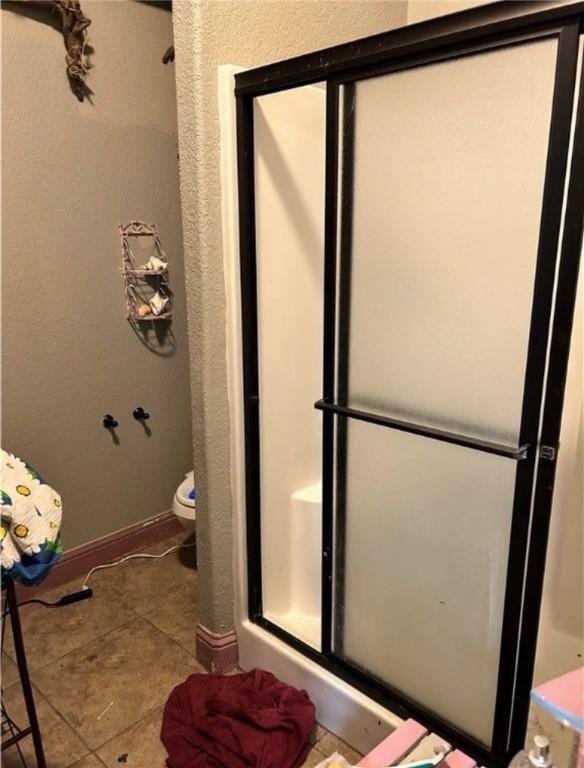 bathroom featuring tile patterned floors, toilet, and walk in shower