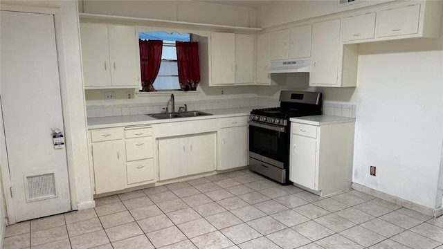 kitchen with gas stove, light tile patterned floors, sink, and white cabinetry