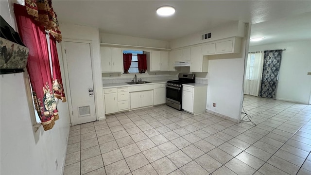 kitchen with decorative backsplash, gas range, sink, light tile patterned floors, and white cabinets