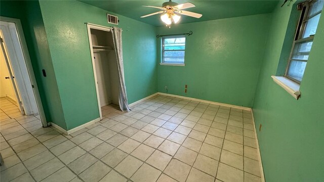 unfurnished bedroom with ceiling fan, light tile patterned flooring, and a closet