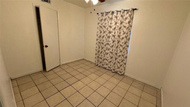 tiled spare room with ceiling fan