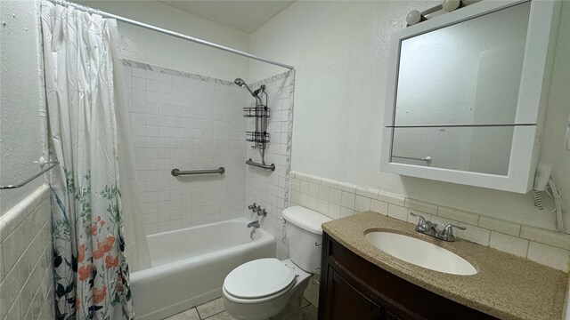 full bathroom featuring tile patterned floors, vanity, shower / bathtub combination with curtain, tile walls, and toilet