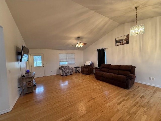 living room with ceiling fan with notable chandelier, vaulted ceiling, and light hardwood / wood-style flooring