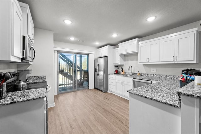 kitchen featuring white cabinetry, sink, stainless steel appliances, light stone counters, and light wood-type flooring