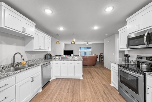 kitchen featuring sink, kitchen peninsula, decorative light fixtures, white cabinetry, and stainless steel appliances