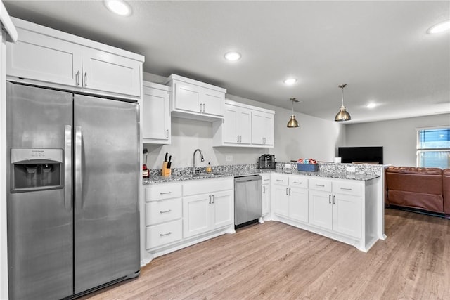 kitchen with pendant lighting, white cabinets, stainless steel appliances, and sink