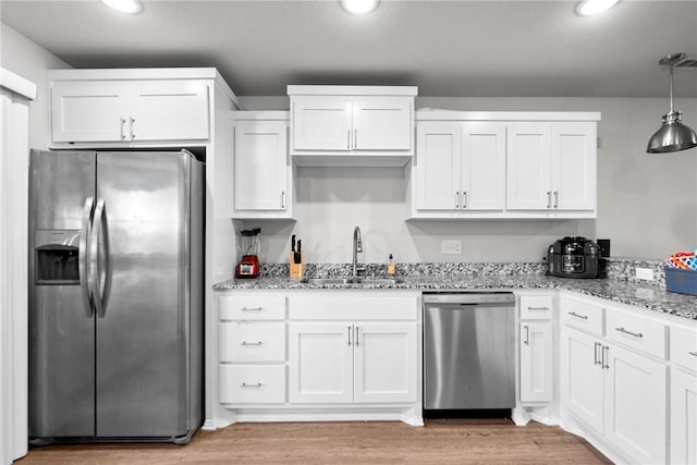 kitchen with white cabinets, decorative light fixtures, sink, and stainless steel appliances