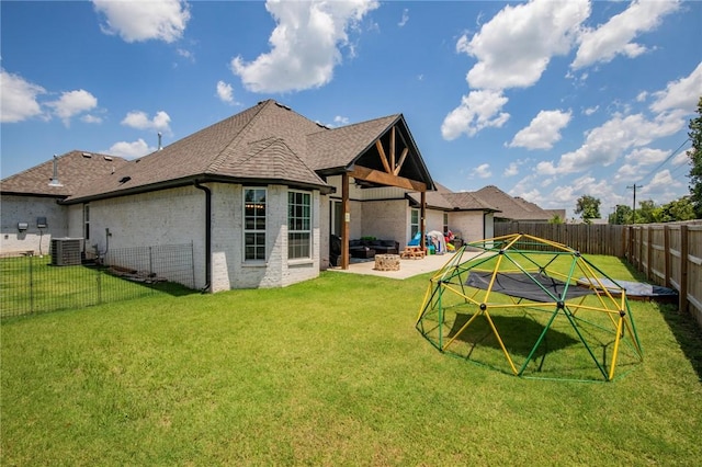 rear view of property featuring a lawn, a patio, an outdoor fire pit, and central AC