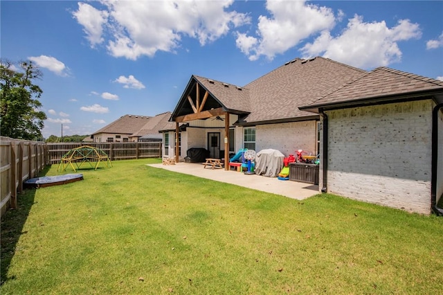 rear view of house featuring ceiling fan, a patio area, and a lawn