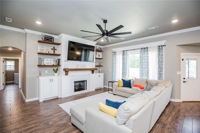 living room featuring a tile fireplace, plenty of natural light, and ornamental molding