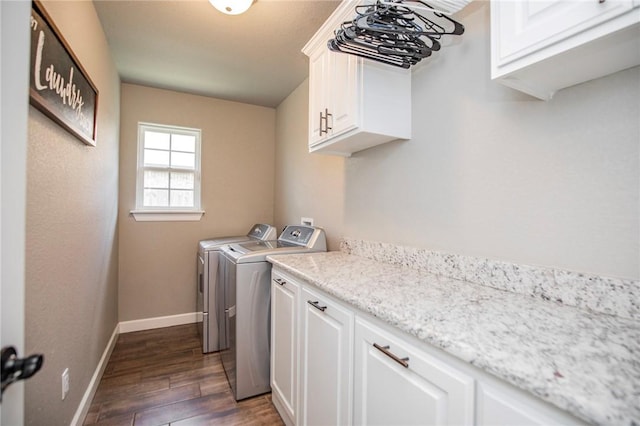 laundry room featuring dark wood-type flooring, washer and clothes dryer, and cabinets