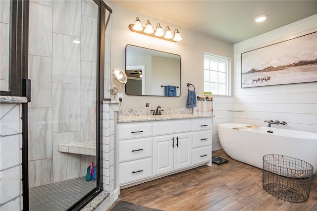 bathroom with hardwood / wood-style floors, vanity, and independent shower and bath