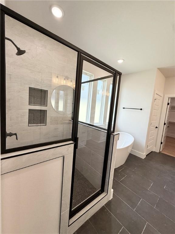 full bathroom with a stall shower, a freestanding bath, baseboards, tile patterned flooring, and recessed lighting