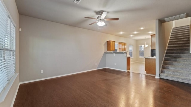 unfurnished living room with ceiling fan with notable chandelier and wood-type flooring