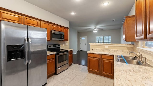 kitchen with light stone counters, stainless steel appliances, ceiling fan, sink, and light tile patterned flooring