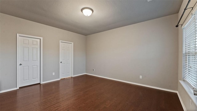 unfurnished bedroom with dark wood-type flooring and a textured ceiling