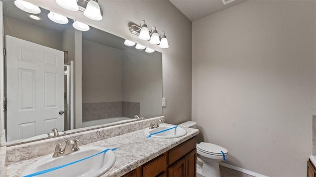 bathroom with a tub to relax in, vanity, and toilet