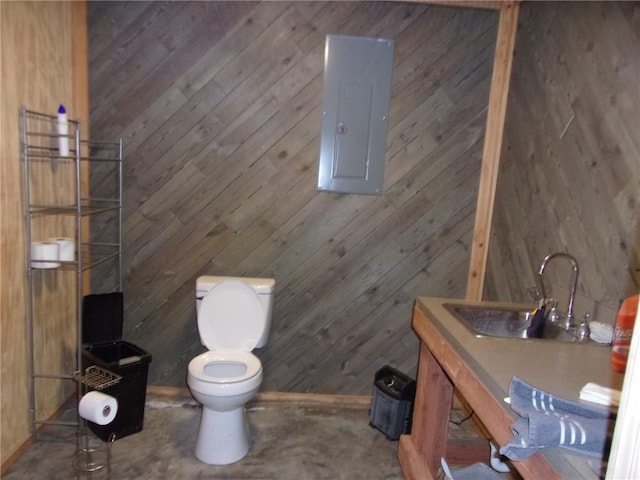 bathroom with sink, electric panel, wooden walls, and toilet