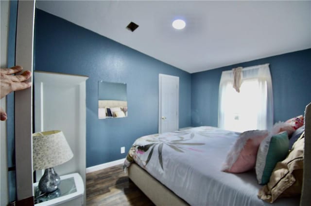 bedroom with lofted ceiling and dark hardwood / wood-style floors