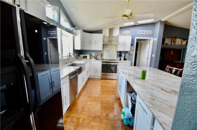 kitchen with black refrigerator with ice dispenser, vaulted ceiling, wall chimney range hood, white cabinets, and range