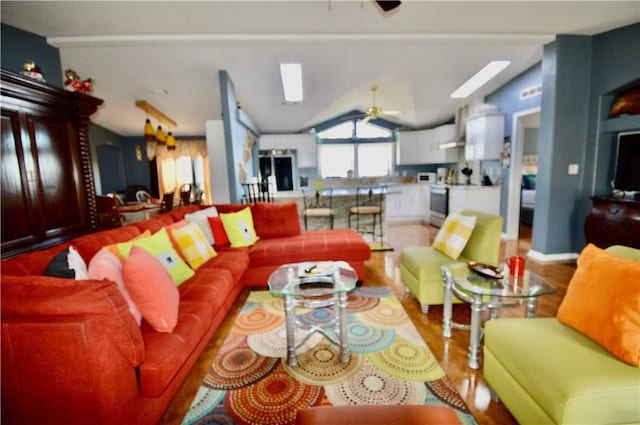 living room featuring lofted ceiling with skylight, ceiling fan, and wood-type flooring