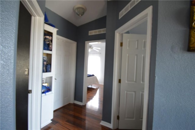 corridor with vaulted ceiling and dark hardwood / wood-style floors