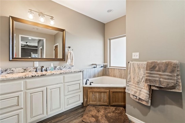 bathroom with hardwood / wood-style flooring, vanity, ceiling fan, and a bath