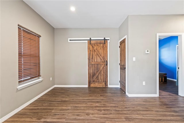 unfurnished room with a barn door and dark hardwood / wood-style flooring