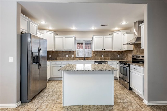 kitchen with white cabinets, wall chimney range hood, sink, appliances with stainless steel finishes, and a kitchen island